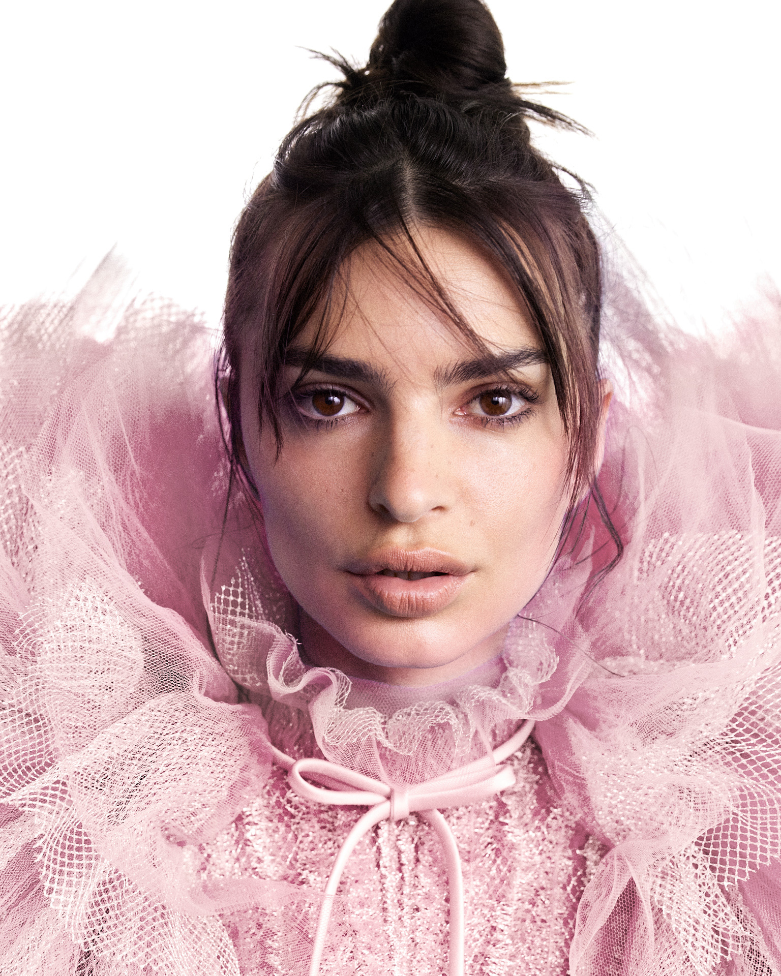 Portrait close-up of a model in a pink ruffled tulle top, looking straight at the camera